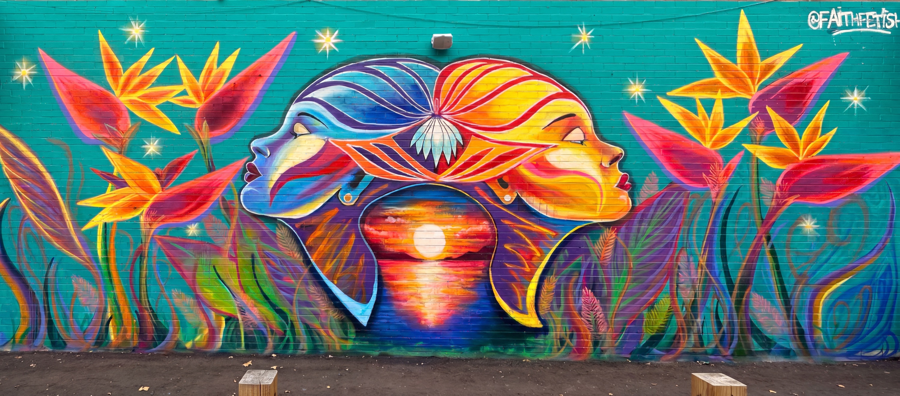 Uncle Betty's street art mural in Toronto: two faces joined by a sunset among birds of paradise