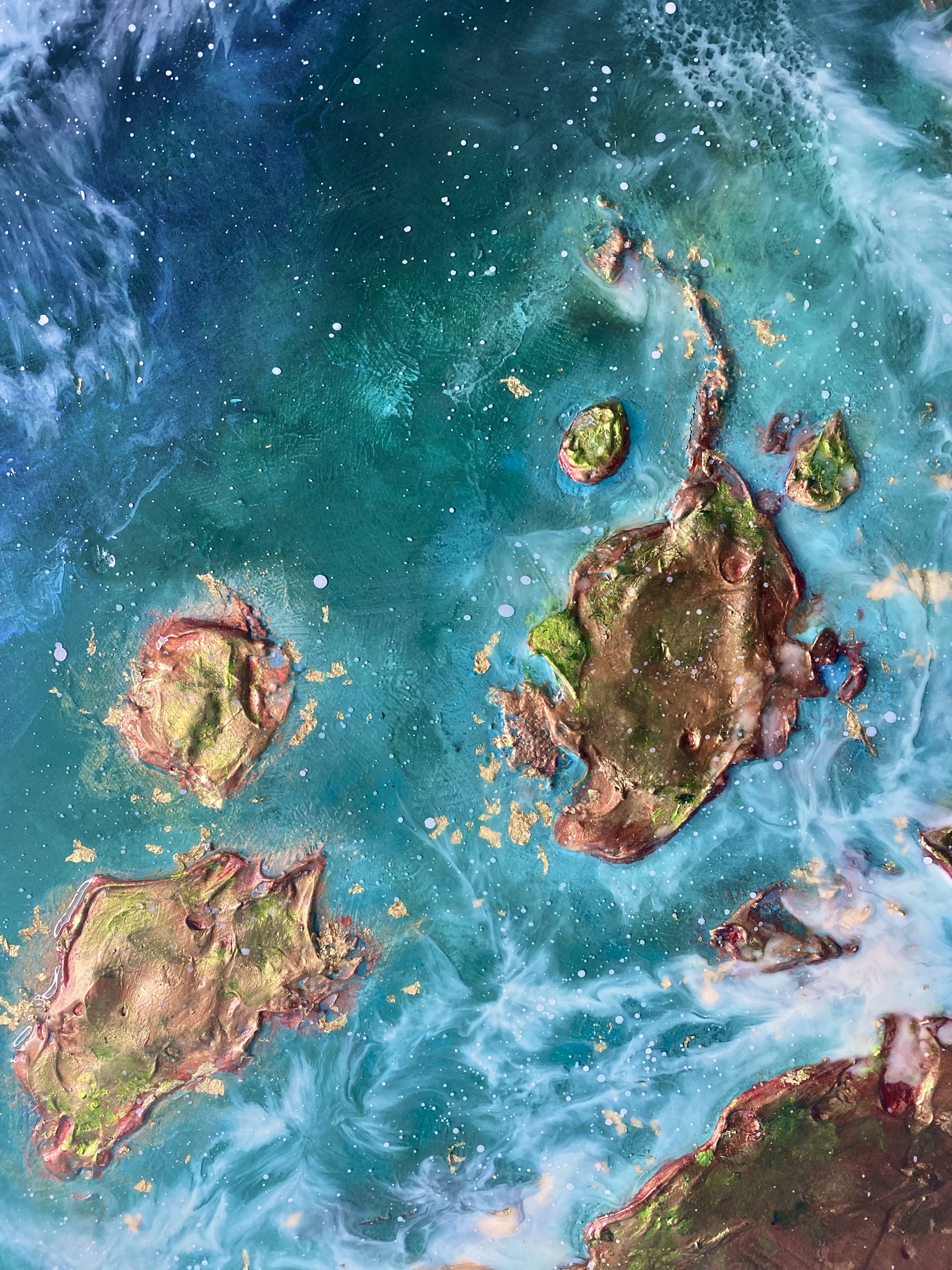 Resin artwork of turquoise sea around gold-leaf islands