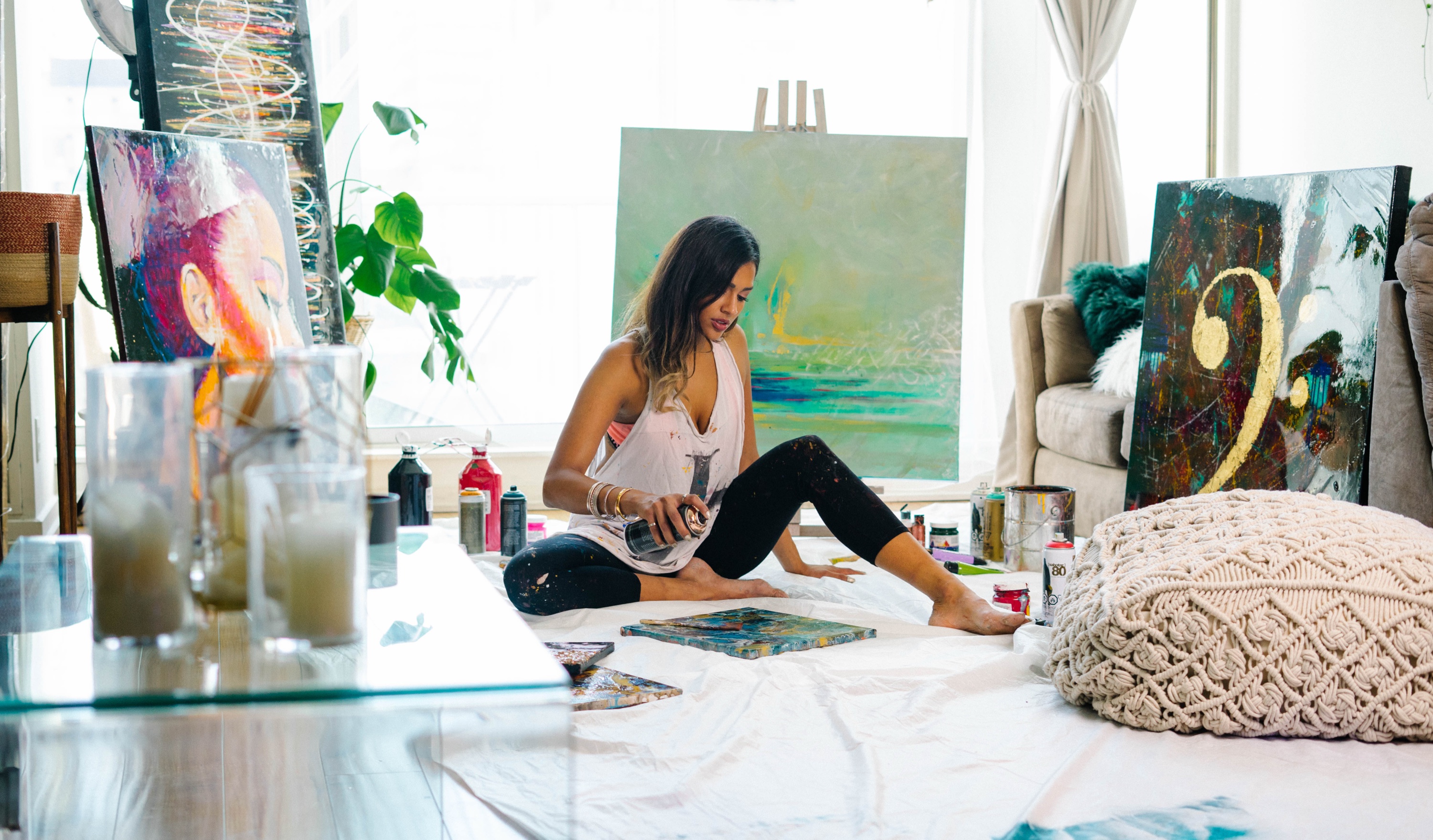 Faith on her studio floor surrounded by her paintings