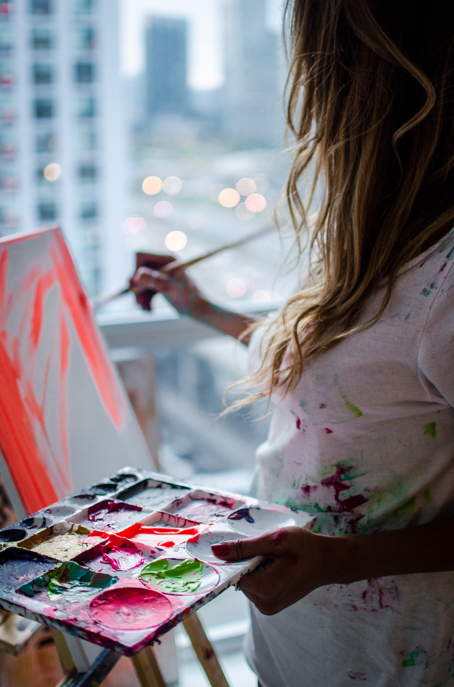 Faith holding a paint palette beside a window